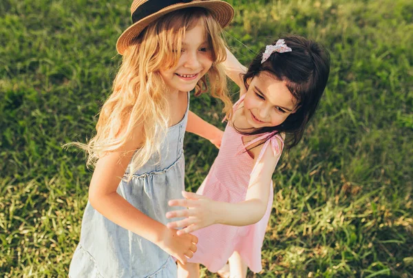 Glücklich zwei positive Kinder, die zusammen spielen. Zwei kleine Mädchen genießen die Sommertage im Park. zwei Schwestern, die sich im Freien an der Sonne amüsieren. Jugend- und Freundschaftskonzept — Stockfoto