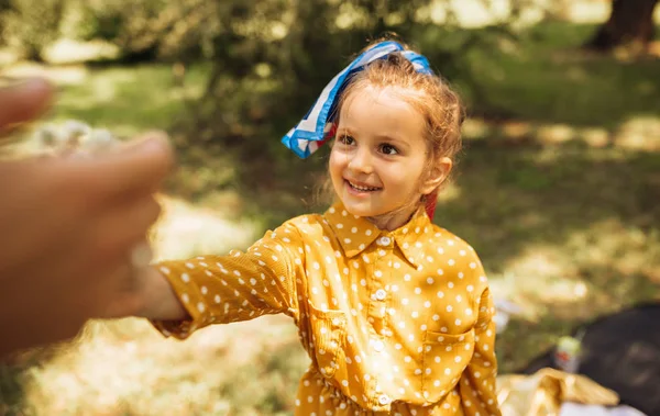 자연 배경에서 그녀의 어머니에게 꽃을주는 긴 금발 머리와 사랑스러운 귀여운 소녀의 야외 이미지입니다. 공원에서 놀고 즐기는 행복한 아이. — 스톡 사진