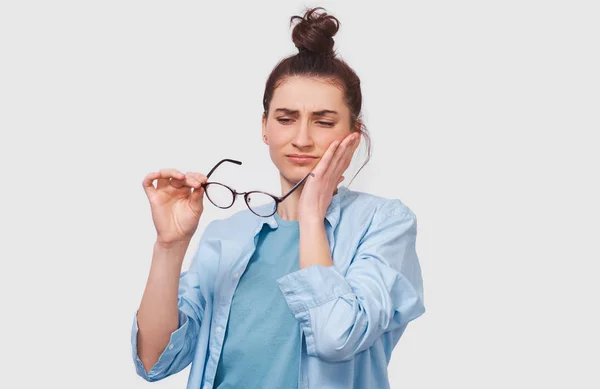 Cuestionada joven bonita tiene expresión de pensamiento, mirando a través de sus gafas transparentes. Chica dudosa lleva gafas no puede hacer elección, ha cuestionado la expresión, en la pared blanca — Foto de Stock