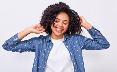 Mavi denim gömlek giymiş memnun genç Afrikalı Amerikalı kadın, kafasına el tutarak, mutlu hissediyor. Pozitif Afrikalı Amerikan kadın geniş beyaz duvar üzerinde poz gülümseyen