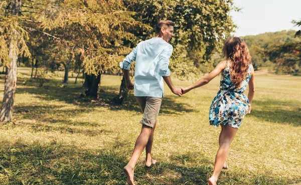 Rear view of romantic couple in love dating outdoors at the park on a sunny day. Happy couple in love walking and playing together on the grass in the nature background. Valentine's day. Couple goals — Stock Photo, Image