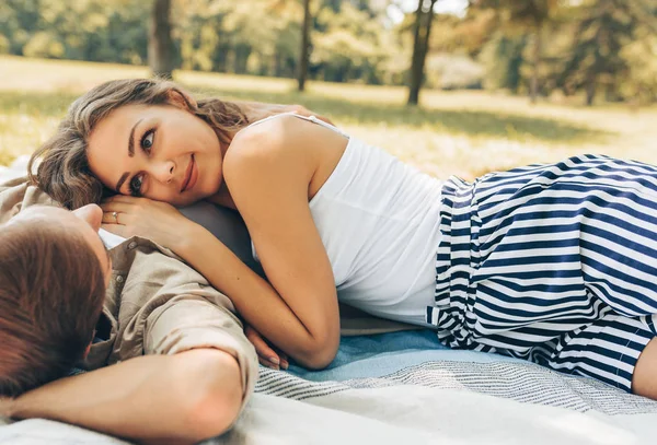 Beautiful couple in love dating outdoors at the park on a sunny day. Happy couple lying on the grass during picnic in the nature background. Valentine day. — Stock Photo, Image