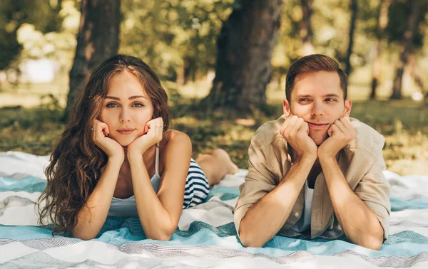 Upset couple feeling sad to each other lying outdoors at the park on a sunny day. Unhappy couple lying on the blanket during picnic, have some problems in relationship in the nature background. — Stock Photo, Image