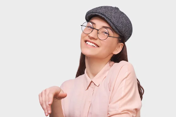 Candid portrait of joyful young woman, smiling and looking to tthe camera, wearing pink shirt and round transparent spectacles. Pretty girl student feels happy during her conversation with friend. — Stock Photo, Image