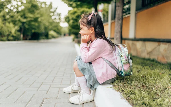 美しい小さな女の子の未就学児の笑顔とバックパックで屋外の玄関先に座っている水平側図。幼稚園の後にリラックス幸せな子供のトドラーの生徒。人と教育の概念 — ストック写真