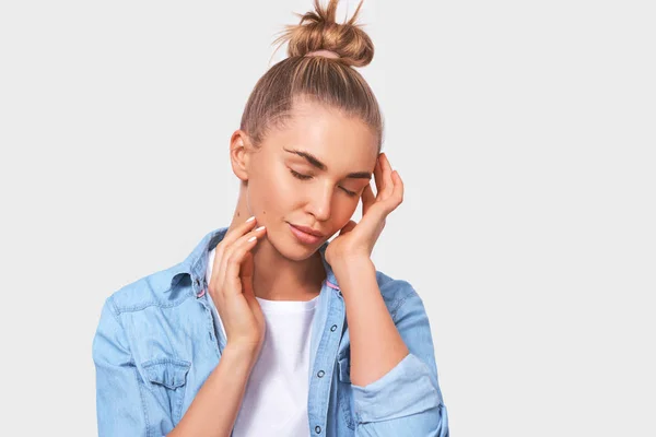 Gros portrait de jeune femme blonde franche touchant sa peau douce parfaite du visage avec les doigts, les yeux fermés, posant sur fond blanc. Jolie femelle avec de la crème pour le visage. Peuple, beauté et santé — Photo