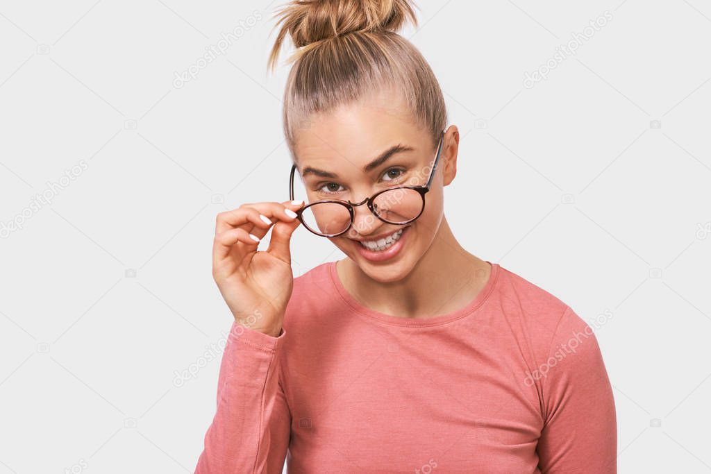 Studio closeup portrait of young woman frowning puzzled faces. Beautiful female woman looking through transparent eyewear at someone aside. People and emotions concept