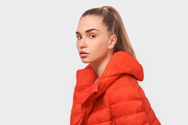 Allvarlig blond ung kvinna som tittar på kameran, dressing i röd jacka, isolerad över vit Studio bakgrund. Människor och känslor Concept — Stockfoto