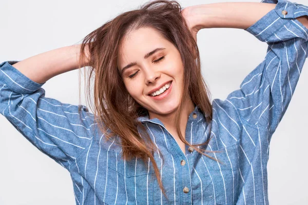 Candid shot of pleased young woman dressed casual striped blue shirt, wake up in the morning. Positive girl posing against white studio backround. People emotions — Stock Photo, Image