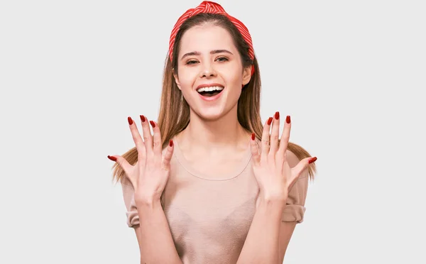 Retrato de surpreso bela jovem mulher tem expressão surpreendente. Mulher muito feliz, de mãos dadas com unhas vermelhas, parecendo animado posando sobre fundo branco. Pessoas emoções Imagem De Stock