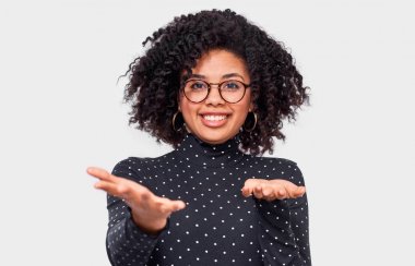 Şaşkın Afro-Amerikan genç kadın omuz silkmek, belirsiz görünüyor, açık el avuç içi ile karışık, şüpheleri vardır. Koyu tenli kadın choise yapamaz. İnsanlar duygu ve duygu kavramı.