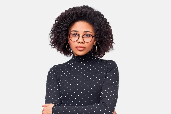 Imagen de una joven afroamericana bonita, vestida con ropa casual y gafas. Afro mujer en camisa negra de manga larga posando sobre pared blanca. Concepto de personas y emociones — Foto de Stock
