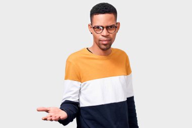 Genç Afro-Amerikan adam eliyle bir şeyler teklif etti. Koyu tenli erkek öğrenci renkli kazak ve yuvarlak şeffaf gözlük giyiyor