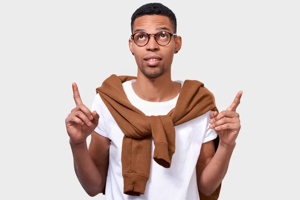 Bild des smarten afrikanisch-amerikanischen jungen Mannes zeigt mit zwei Zeigefingern auf leeren Kopierraum, für Ihren Werbetext, in lässigem Outfit und Brille. Werbung und Ethnizitätskonzept — Stockfoto