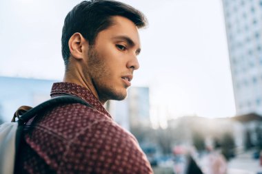 Arka tarafta sokakta sırt çantası ile yakışıklı kafkas adam portresi. Genç iş turisti şehirde dışarıda yürüyor. Kentsel yaşam tarzı kavramı.