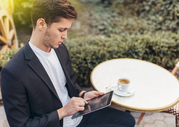Chytrý obchodník s tabletovým tabletem při snídani v kavárně, podnikatel s kávou v ruce, zatímco ráno na terase četl novinky o tabletovém tabletu. Koncepce podniků a technologií. — Stock fotografie