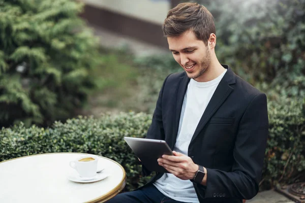Vrolijk glimlachend blanke student houdt Tablet-apparaat surfen op internet en het controleren van newsfeed op sociale media tijdens koffiepauze in modern café in de stad. Technologie en bedrijfsconcept. — Stockfoto