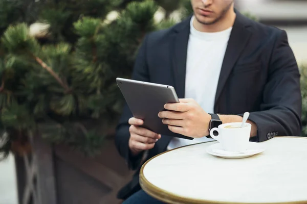 Cropped head shot of Caucasian man in casual suit bying online orders via the Internet. Successful European businessman reading news from tablet device.