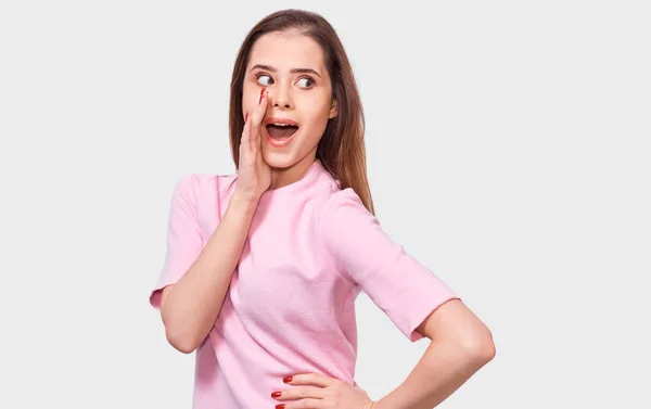 Verbaasd mooie jonge vrouw kijken naar de camera met verbaasde uitdrukking. Verbaasd vrouw, hand op de mond houden, kijken geschokt poseren instudio. Mensen en emoties — Stockfoto