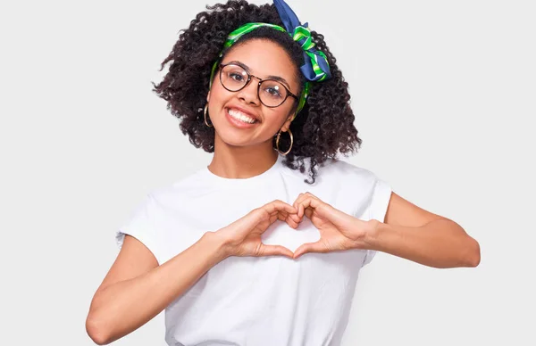 Lächelnde junge Afrikanerin, die mit Fingern Herzformen herstellt. schöne Afro-Frau in weißem T-Shirt und Brille, zeigt Herz-Geste mit beiden Händen, Liebeszeichen, posiert auf weißem Hintergrund — Stockfoto