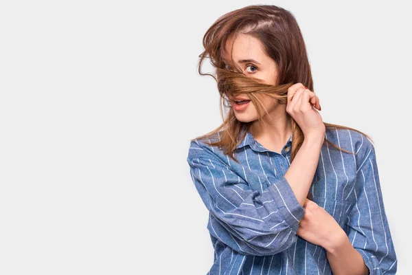 Mulher alegre brincando com o cabelo, posando sobre fundo branco. Bonito sorriso feminino feliz com um cabelo bagunçado, isolado na parede branca — Fotografia de Stock