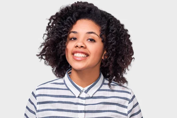 Retrato de mujer joven afroamericana bonita con sonrisa positiva, mirando a la cámara, tiene expresión alegre. Encantadora hembra de piel oscura tiene emociones positivas . — Foto de Stock