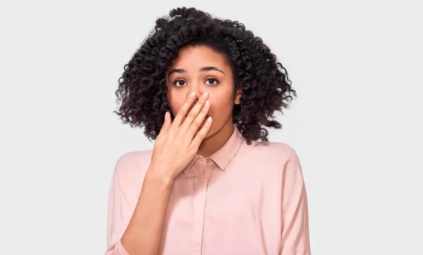 Mujer joven afroamericana asombrada tiene expresión asombrada. Hermosa hembra Afro oye algo increíble, mantiene las manos abiertas, aisladas sobre fondo blanco. Concepto de emociones —  Fotos de Stock