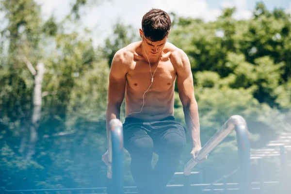 Althelte jovem fazendo exercícios na barra transversal horizontal no sportsground. Bonito muscular shirtless masculino treinamento duro, desportista trabalhando fora . — Fotografia de Stock