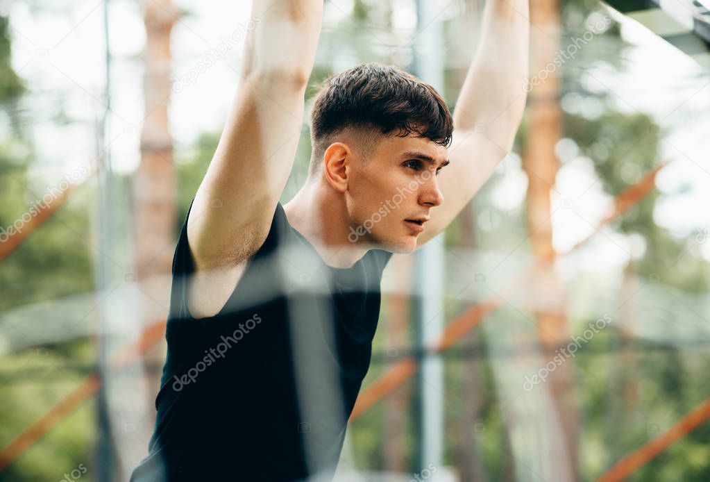 Healthy young man standing outdoors at sportsground in the park, preparing for workout training. Confident young fitness man ready of workout. People and sport.