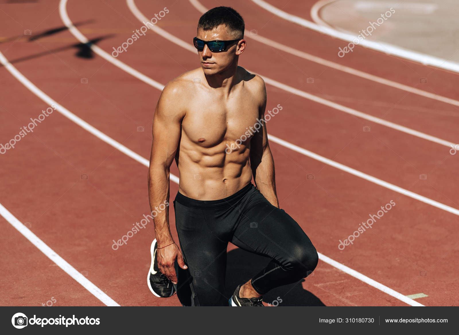 Image of shirtless young athlete man preparing for running on racetrack