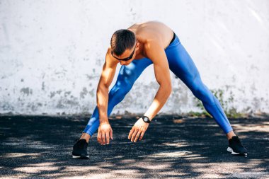 Sporcu beton duvara karşı açık havada egzersizleri önce germe. Atlet erkek dışında egzersiz sonrası uzanır. Spor ve insan kavramı. Metniniz için alan kopyalama