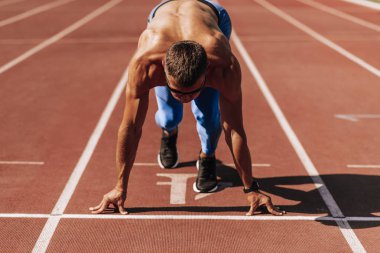 Stadyumda yarış pistinde koşmaya hazırlanan sporcu. Yarışma için eğitim oturumu sırasında erkek koşucu sprint. İnsanlar, spor ve sağlıklı yaşam tarzı