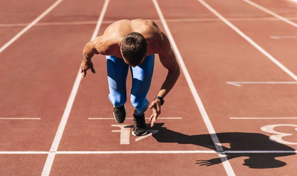 Sprinter adam stadyumda yarış pistinde koşmaya hazırlanıyor. Sporcu, müsabaka için yapılan antrenmanda erkek koşucu koşusu yaptı. İnsanlar, spor ve sağlıklı yaşam tarzı