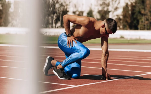 Αθλητής ετοιμάζεται για τρέξιμο στην πίστα αγώνων στο στάδιο. Αθλητής, άντρας δρομέας που τρέχει κατά τη διάρκεια της προπόνησης για τον ανταγωνισμό. Άνθρωποι, Αθλητισμός και υγιεινός τρόπος ζωής — Φωτογραφία Αρχείου