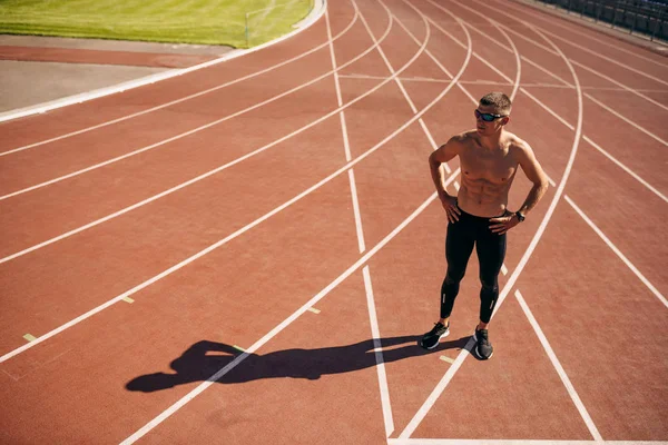 Stadyumda yarış pistinde poz genç atlet adam görünümü yukarıda. Antrenman sırasında profesyonel gömleksiz sporcu. İnsanlar, spor ve sağlıklı yaşam tarzı — Stok fotoğraf