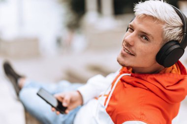 Yakışıklı sarışın adam parkta havanın tadını çıkarıyor kız arkadaşını bekliyor. Parkta açık havada akıllı telefon kullanarak en sevdiği müziği dinlerken mesaj atıyor..