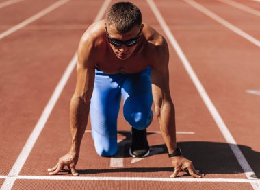 Stadyumda yarış pistinde koşmaya hazırlanan sporcu. Yarışma için eğitim oturumu sırasında erkek koşucu sprint. İnsanlar, spor ve sağlıklı yaşam tarzı