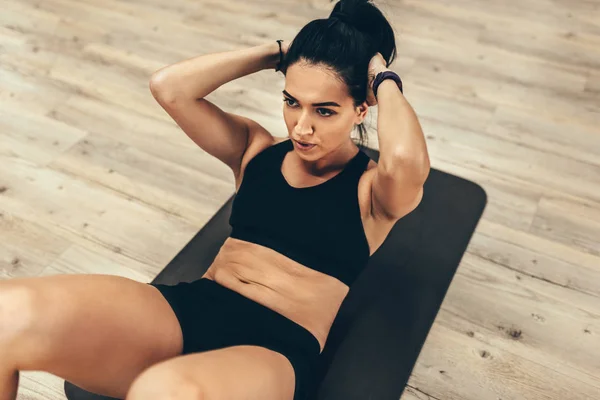 Beeld van een sportvrouw die buikspieroefeningen doet in de sportschool. Vrouw in de sportschool doet buikspieroefeningen in een fitnessclub. Sport, leefstijl en mensen concept — Stockfoto