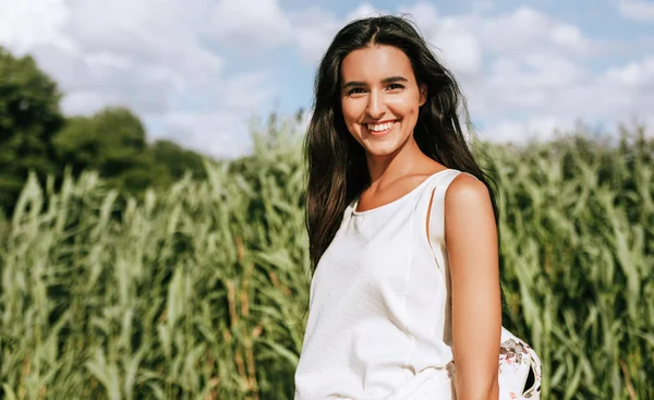 Retrato ao ar livre de bela jovem mulher sorridente com um vento soprando cabelos longos no parque, posando no fundo da natureza . — Fotografia de Stock