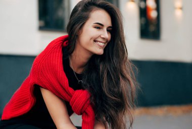 Gorgoeus gülümseyen genç bir kadın dışarıda oturuyor ve fermuarlarını yürümesi için cilalıyor. Esmer kadın, kırmızı kazak ve siyah tişört giyiyor ve şehir caddesinde dinleniyor..