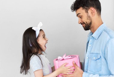 Mutlu kız babaya babalar gününde hediye paketi veriyor. Neşeli küçük kız babasından bir hediye alır..