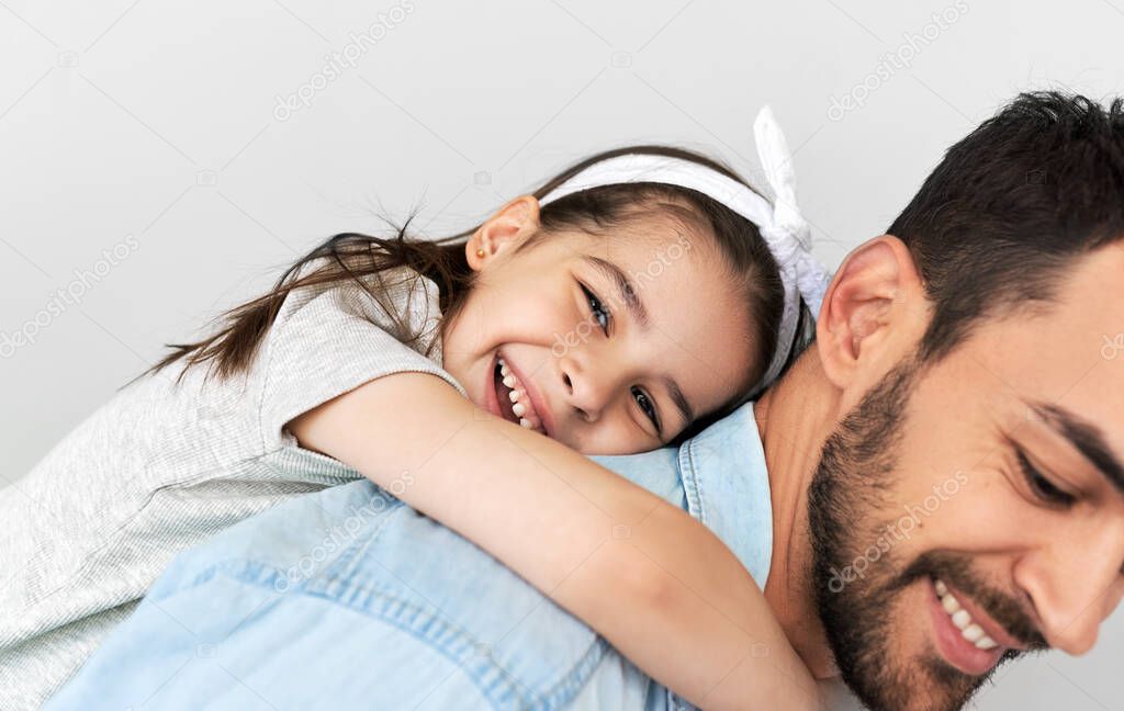 Cute little girl on a piggy back ride with her father. Loving smiling daughter and her dad speanding time together. Daddy and child has joyful expression during playing together on a Father's Day.