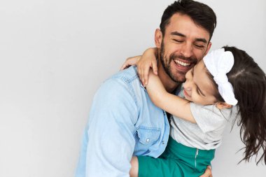 Mutlu babanın stüdyo görüntüsü tatlı kızını kucaklıyor. Babasını ve küçük kızını seviyor, gülümsüyor, sarılıyor ve birlikte vakit geçiriyorlar. Babalar Günü. Çocukluk ve babalık kavramı.