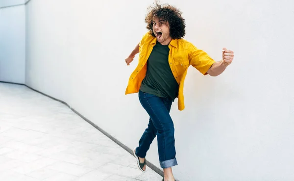 Joven Positivo Con Pelo Rizado Camisa Amarilla Sonriendo Ampliamente Saltando — Foto de Stock