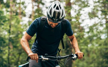 Bisikletli bir adamın dağda bisiklet sürüşünün yatay dış görüntüsü. Bisiklet süren erkek sporcu, doğa arka planında pratik yapıyor. Seyahat ve ekstrem spor konsepti.
