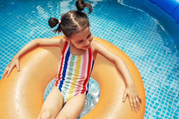 수영장에서 떠다니는 부풀어 오르는 오렌지 위에서 수영복을 어린이의 위에서 보인다 — 스톡 사진