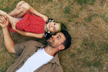 Babamızın kızıyla dışarıda çimlerin üzerinde yattığının en iyi görüntüsü. Parkta babasıyla oynayan mutlu küçük kız. Babacık ve küçük kız birlikte eğleniyor Babalar Günün kutlu olsun