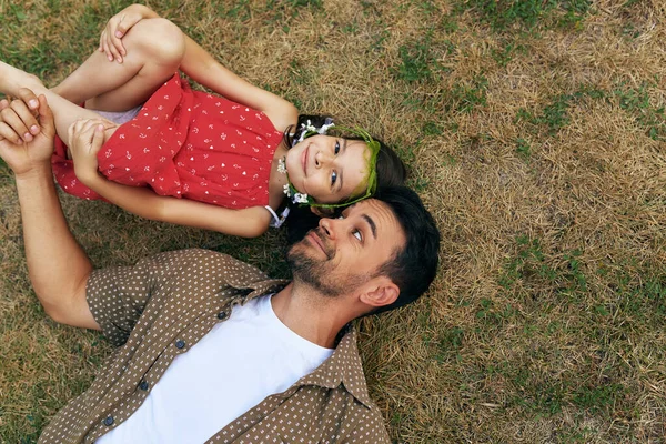 Babamızın kızıyla dışarıda çimlerin üzerinde yattığının en iyi görüntüsü. Parkta babasıyla oynayan mutlu küçük kız. Babacık ve küçük kız birlikte eğleniyor Babalar Günün kutlu olsun