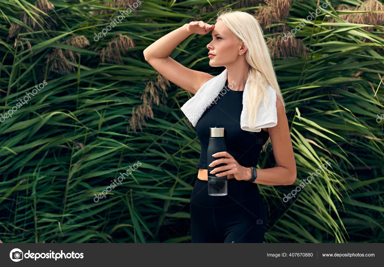 Shot of beautiful female runner standing outdoors holding water