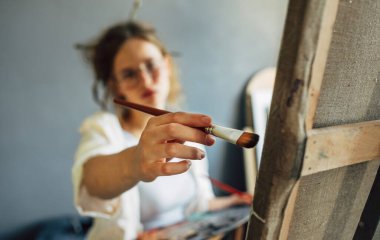 Odaklanamayan çekici bir kadın sanatçı tuval tablosuyla stüdyoda odak noktası ve paleti olan bir resim yapıyor. Atölyedeki profesyonel kadın ressam..